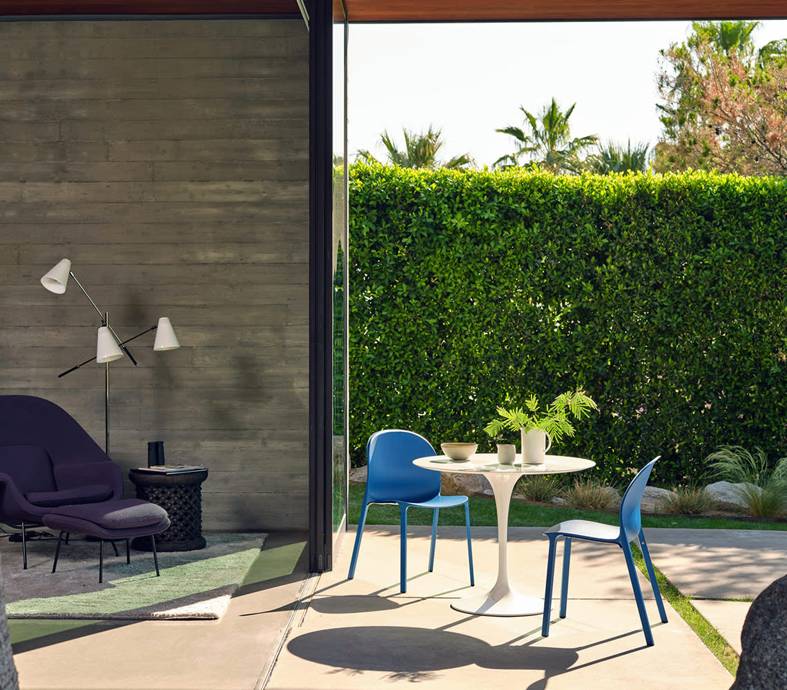 A cozy patio featuring a white table surrounded by two bright blue chairs